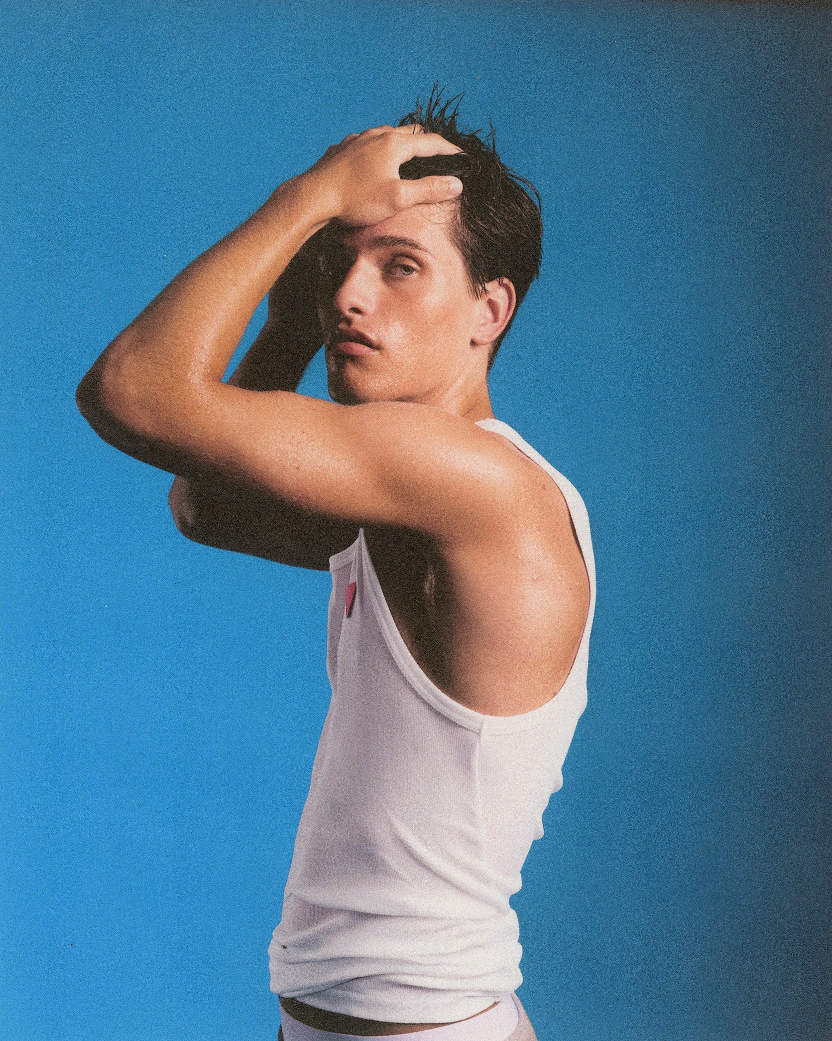 Man in a white tank top against a blue background